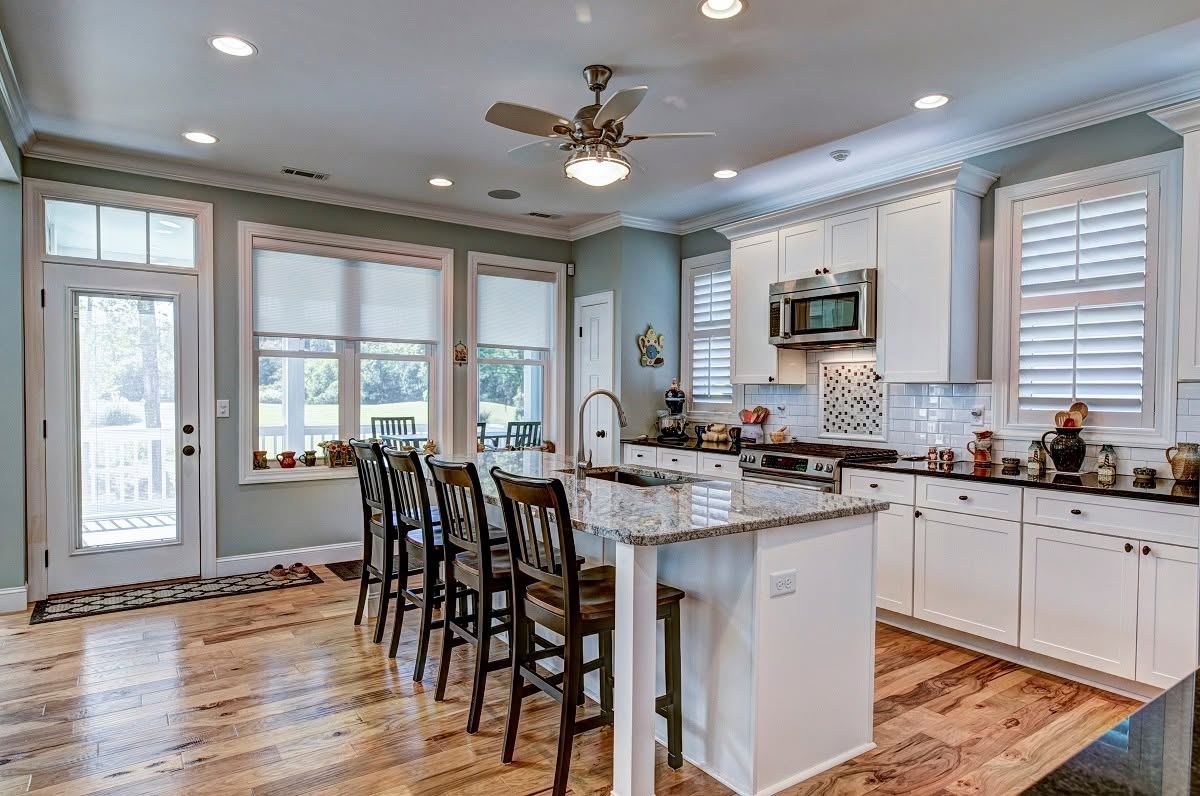 Finished kitchen with white shaker cabinets, island seating and hardwood floors